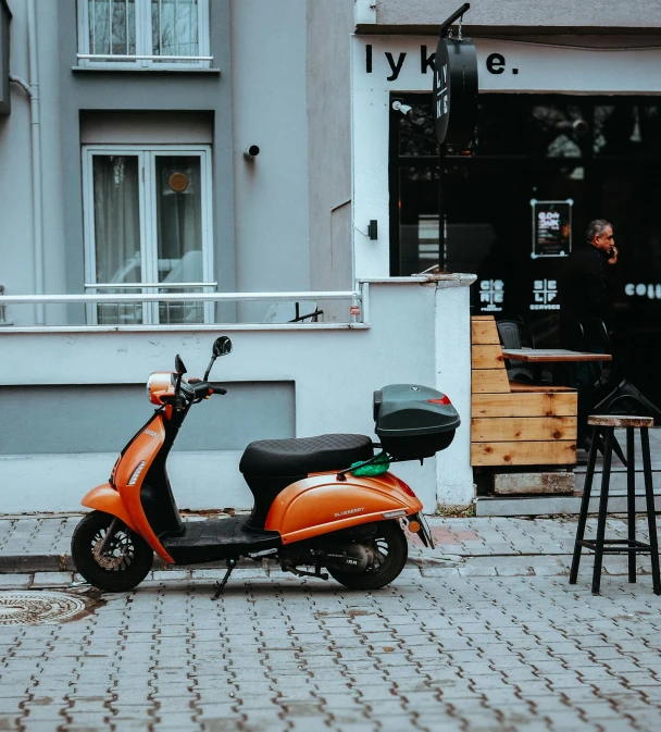 a scooter is parked on the side walk next to an empty table