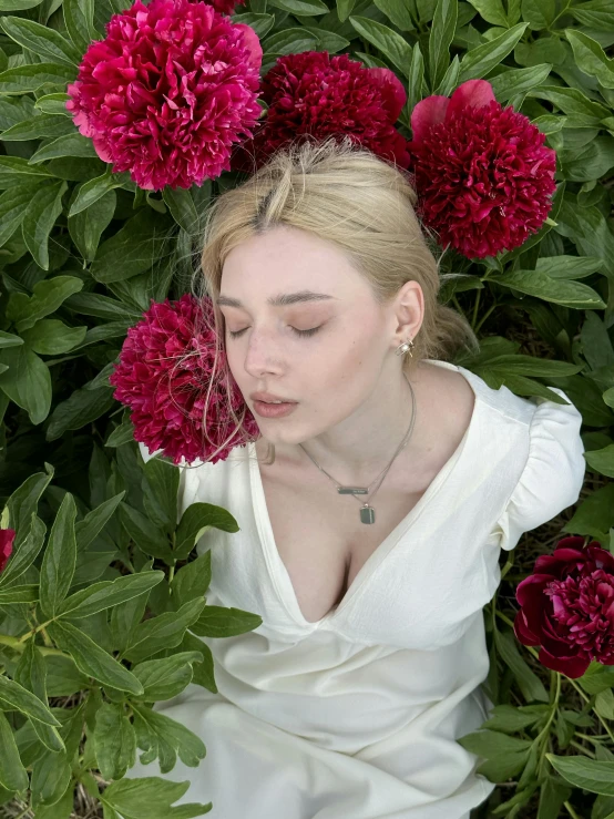 a woman is lying in a bush with flowers