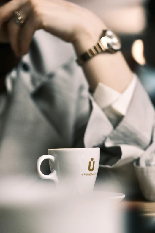 a person sitting at a table holding a cup of coffee