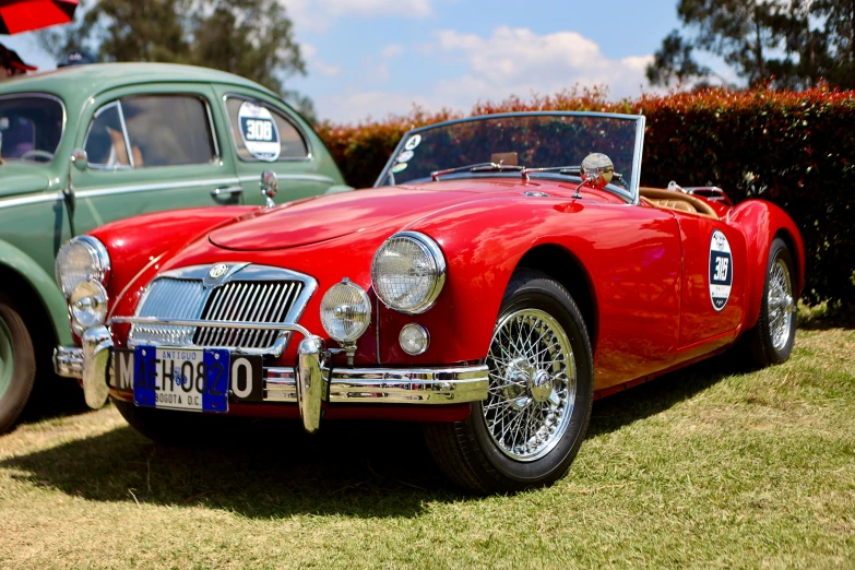 an antique car parked on grass and next to a green antique vehicle