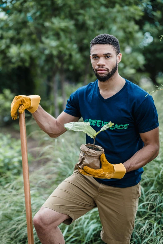 man posing for a pograph while holding bananas in a field