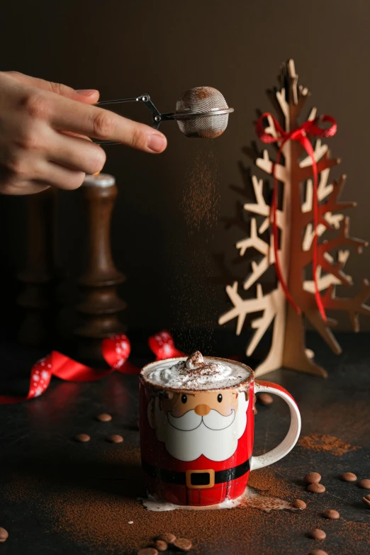 someone scooping coffee into a coffee mug while sprinkled with cocoa