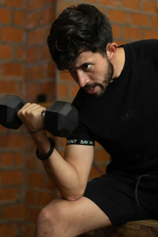 a man with curly hair and beard holding two gray dumbs