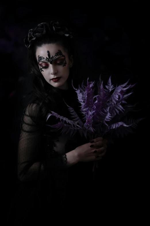 a woman wearing a costume and makeup holding purple feathers