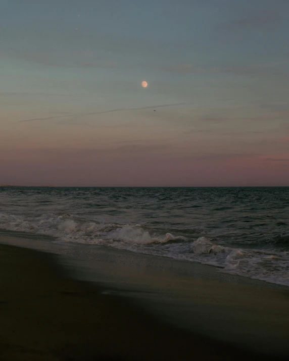 a beach with some waves coming in at sunset