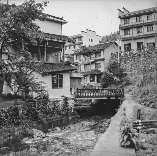 a river runs by some old buildings on a hillside