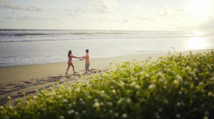 a couple is holding hands as they walk along the beach