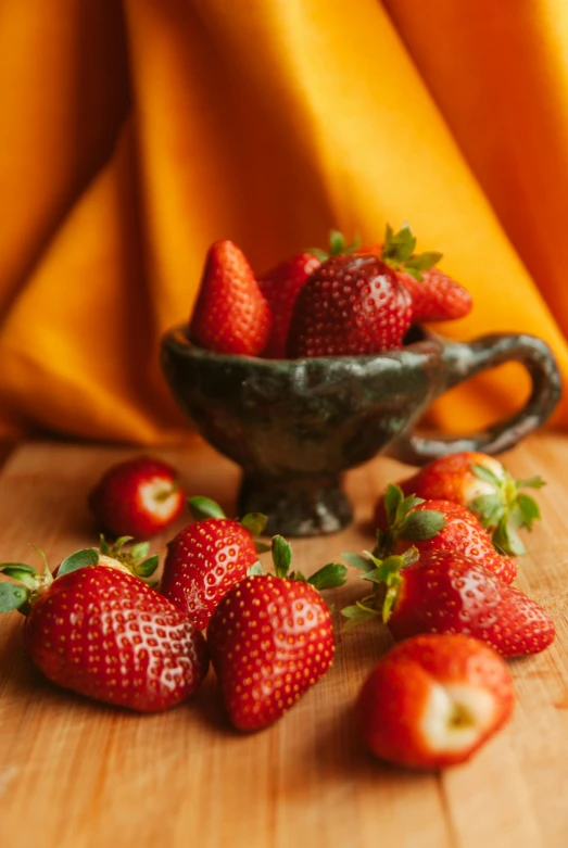 a small bowl filled with strawberries on a wooden surface