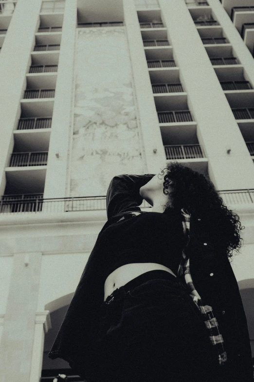 a woman leaning against a building that is tall