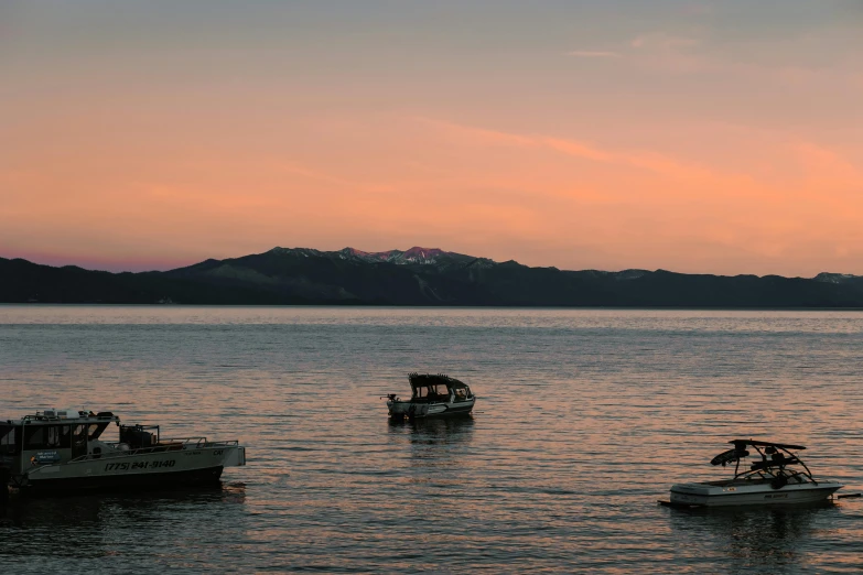 several boats out in the water with mountains and sunset