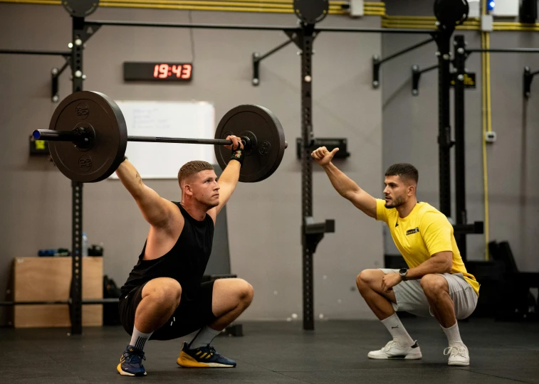 the two men are squatting down with their arms