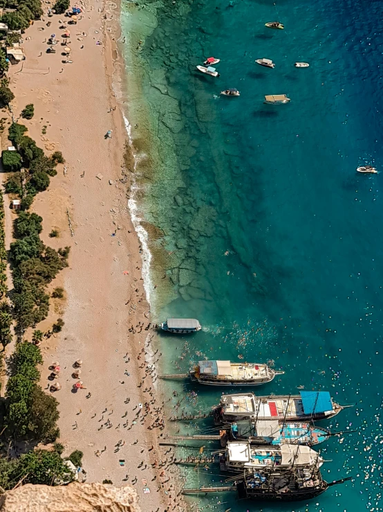 a group of boats floating in the ocean next to a sandy shore