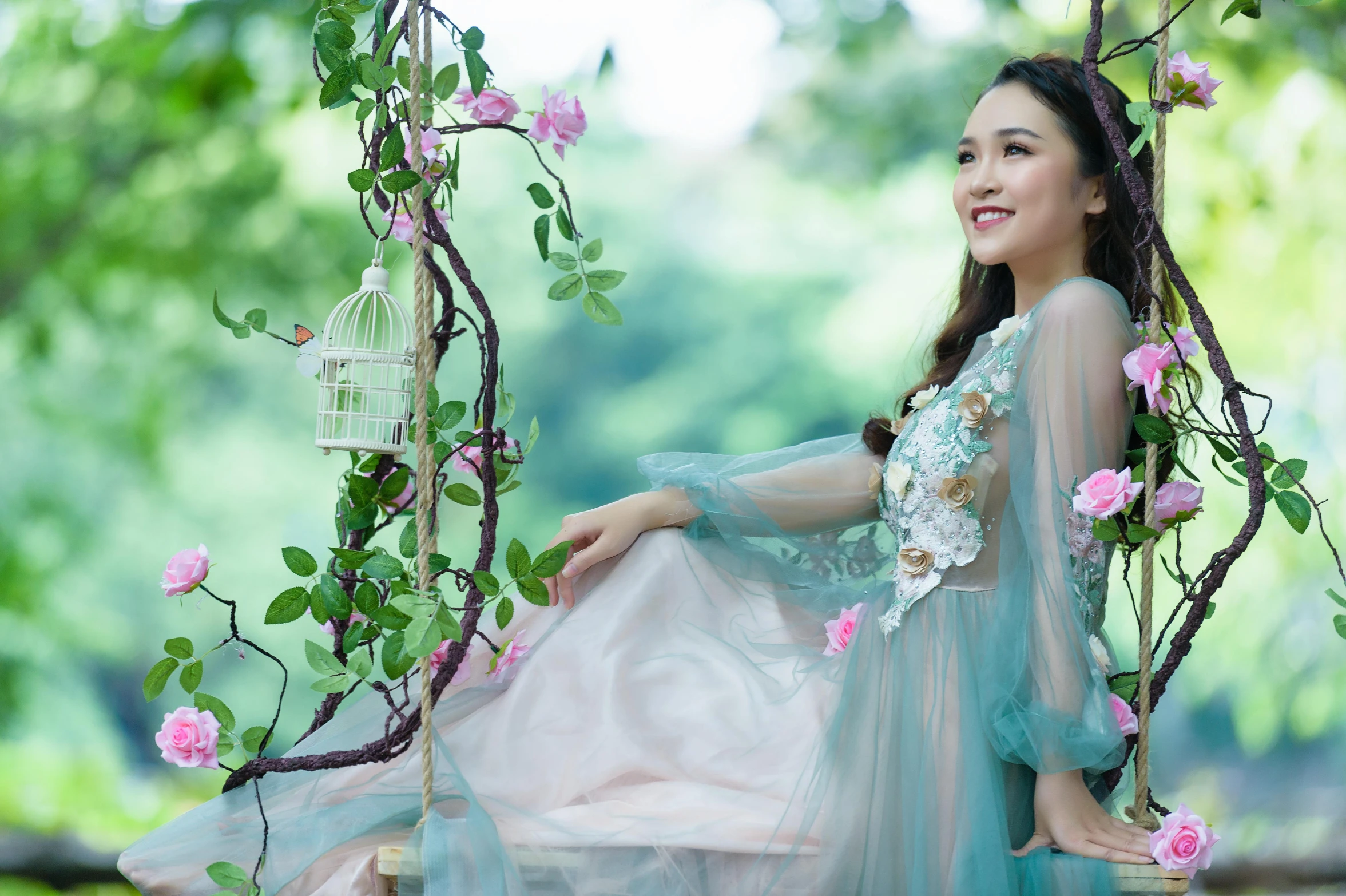 a girl sitting on a tree swing dressed in white