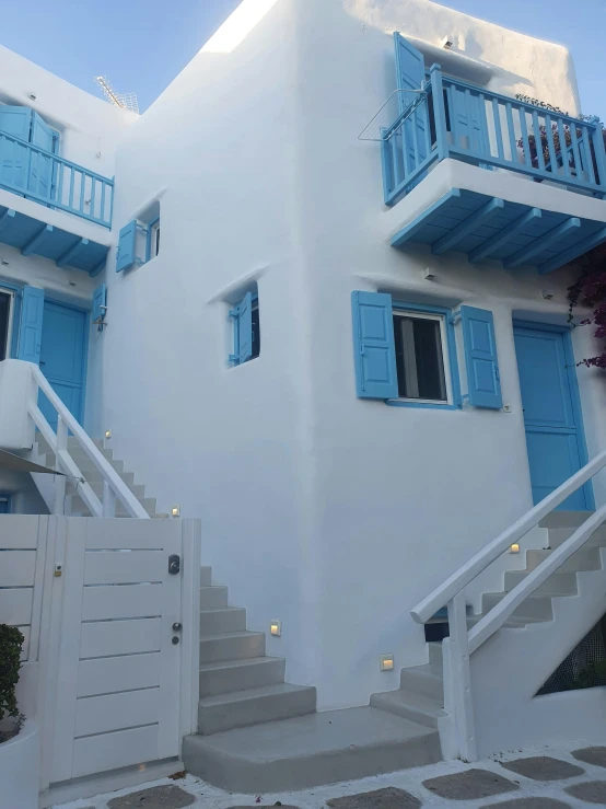 a tall white building with blue doors and a window