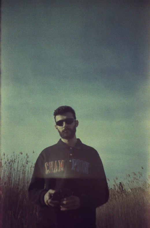 a man wearing sunglasses holding a plate while standing in tall grass