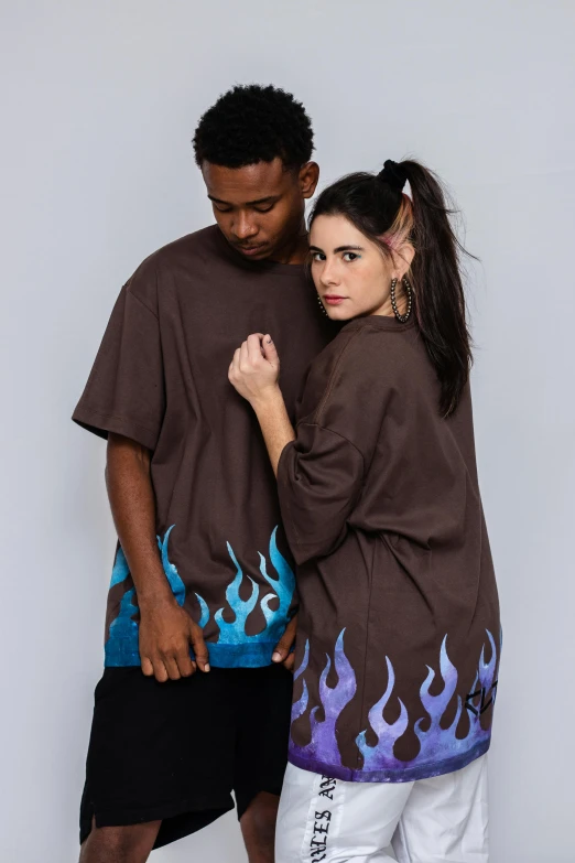 a man and woman stand next to each other, wearing t - shirts with flames