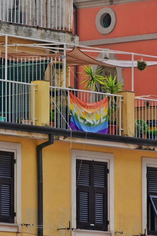 a rainbow colored flag hanging off the side of a building