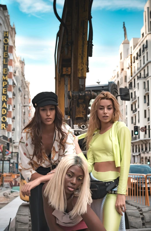 three women stand in front of a giant machinery wheel