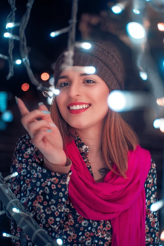 a woman is standing under christmas lights smiling