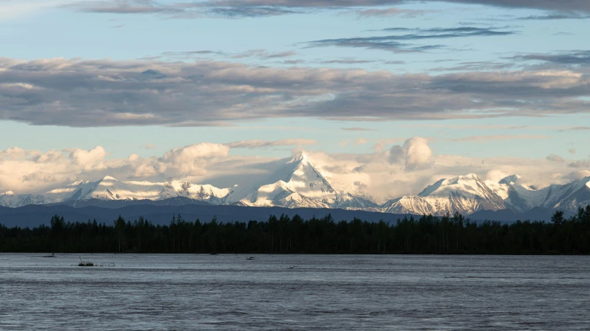 a couple of big snow covered mountains by some water