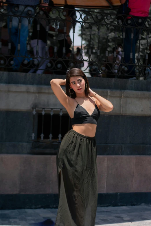 a beautiful young woman in a skirt standing by a fountain