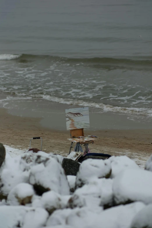 a beach with waves in the background and a piece of artwork on top of a wooden table