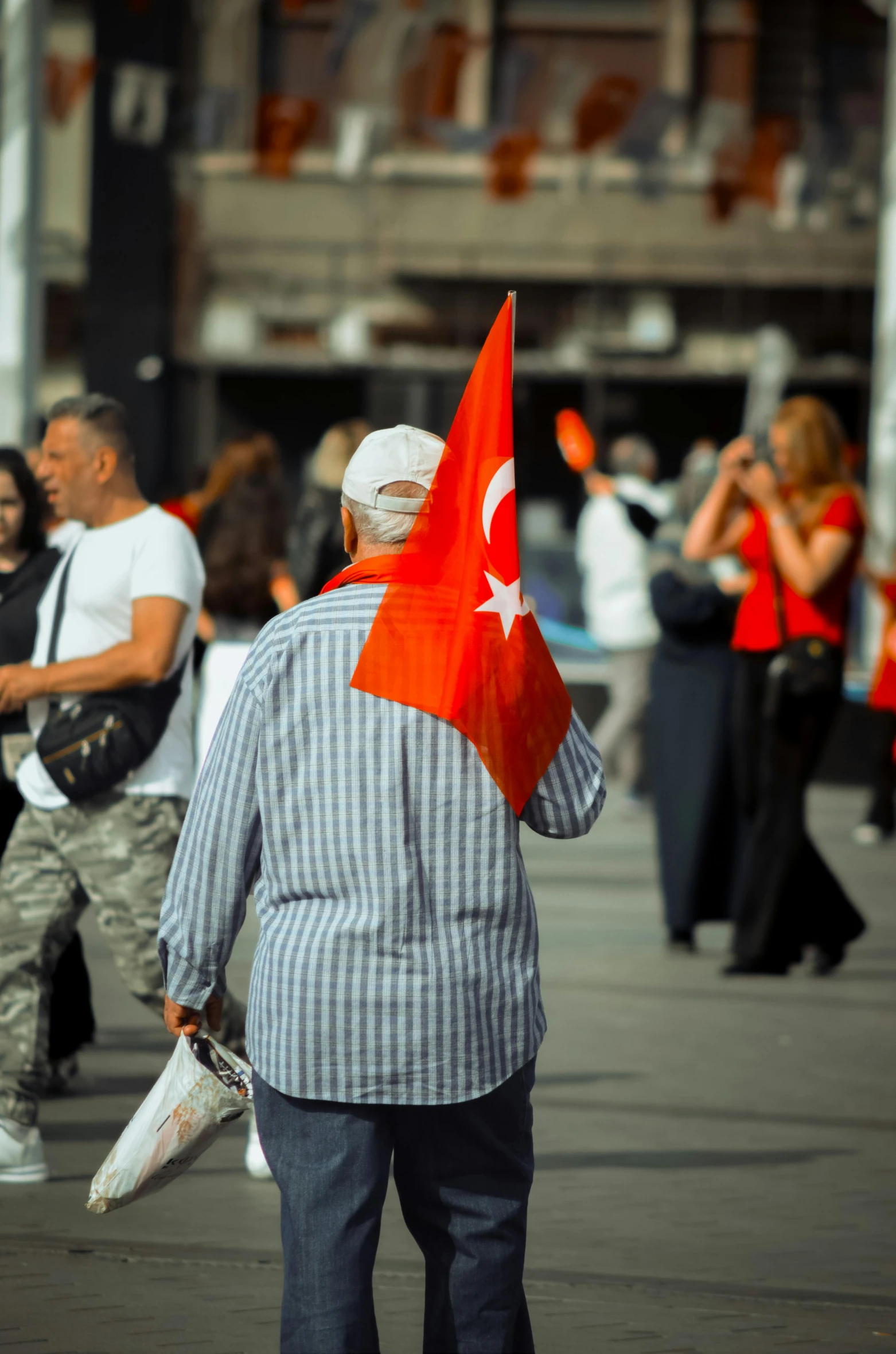 man wearing red and white with flag on street