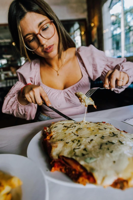 a woman sitting at a table with a plate and pizza