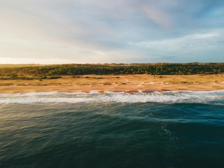 some ocean water and a beach under a cloudy sky