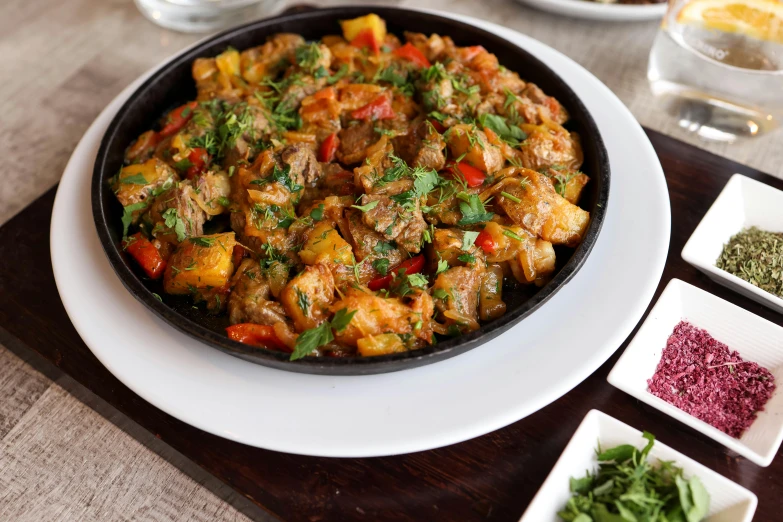 meat and vegetable dish served in plate with various bowls