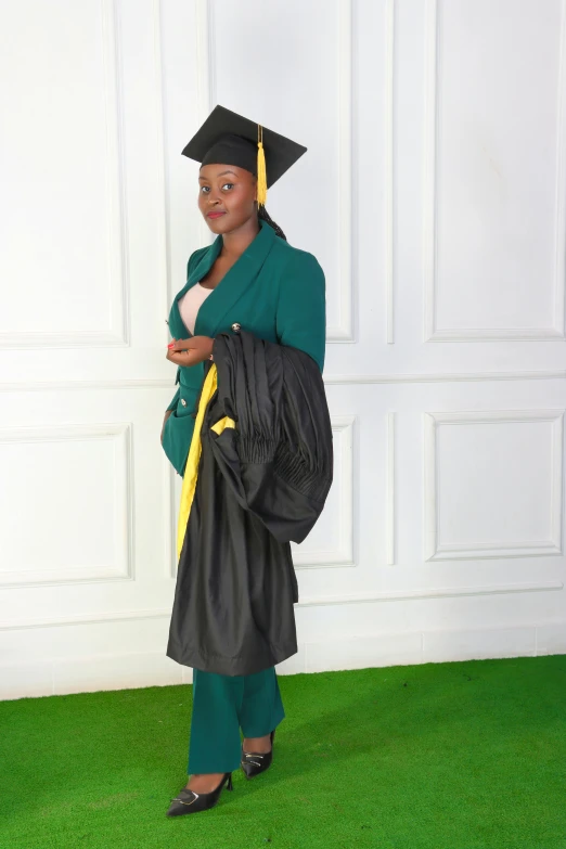 the woman is wearing a black graduation robe and is holding a green bag