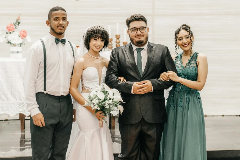 a couple stands holding hands while two women hold a bouquet