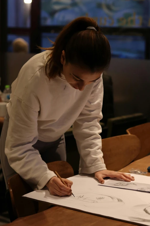 a woman in white shirt writing on paper