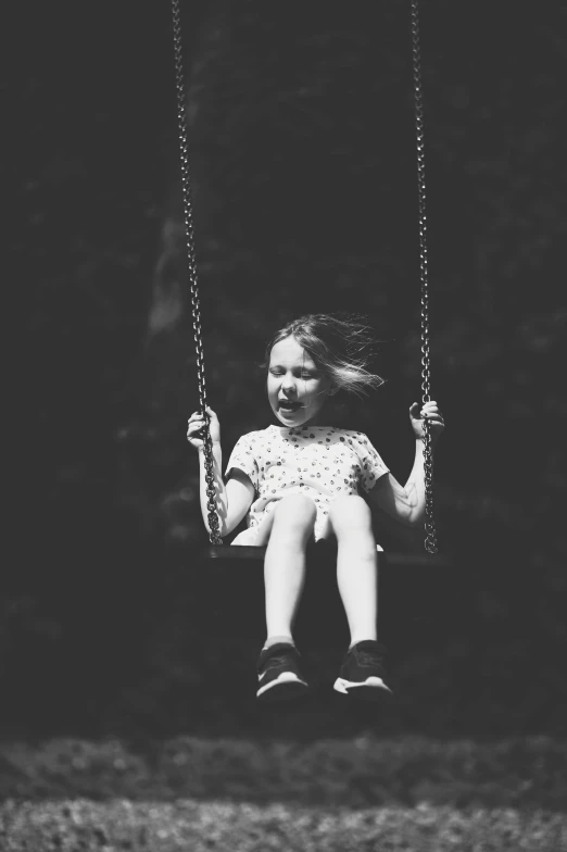 a little girl sitting in a swing outside