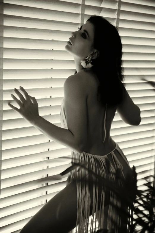 a woman posing in front of blinds with her hands out