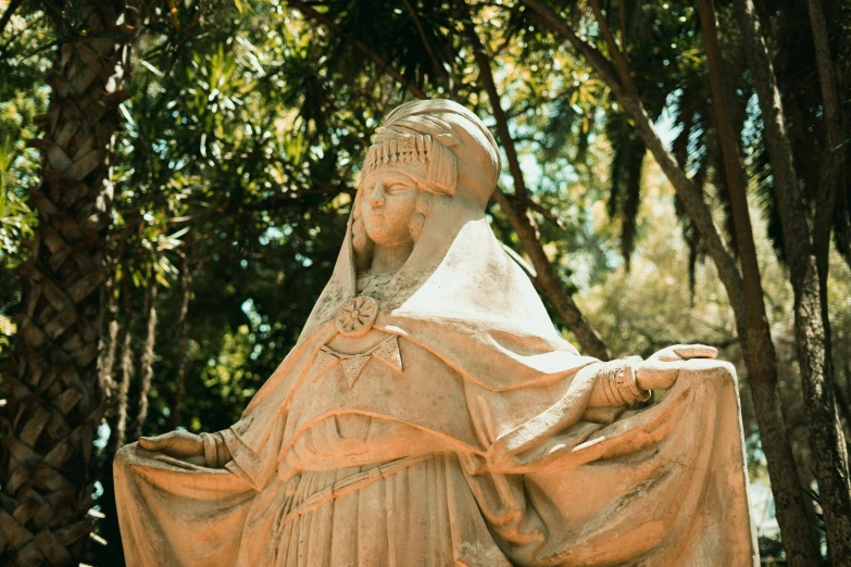 the statue of a lady with a veil and mantle is in a garden