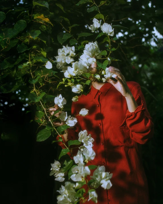 a woman with a red jacket is near some white flowers