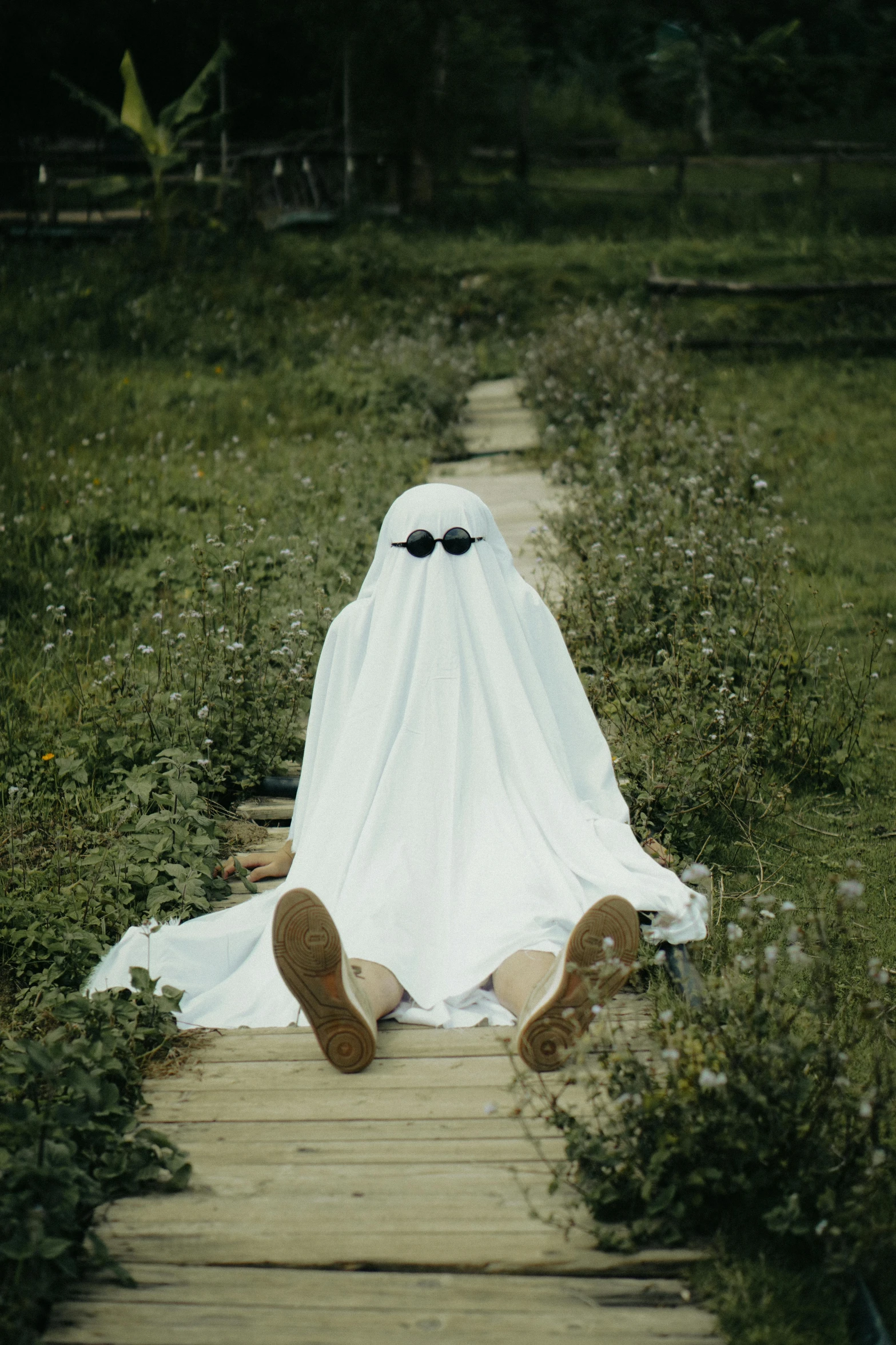 a white ghost is covered in a big white cloth on the end of a path