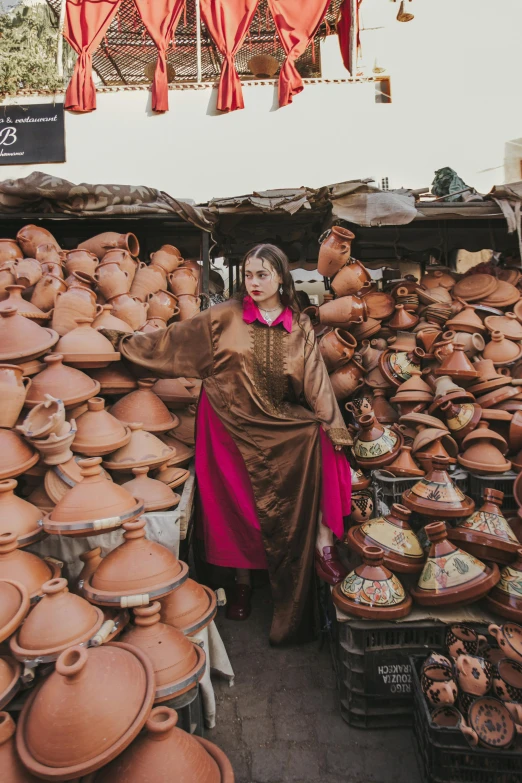 a woman is standing in front of large pots