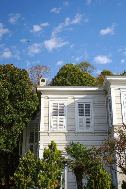 a grey building is shown with white windows and trees