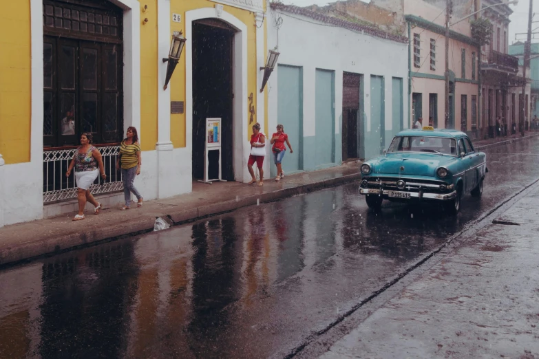 people on the street near an old classic car