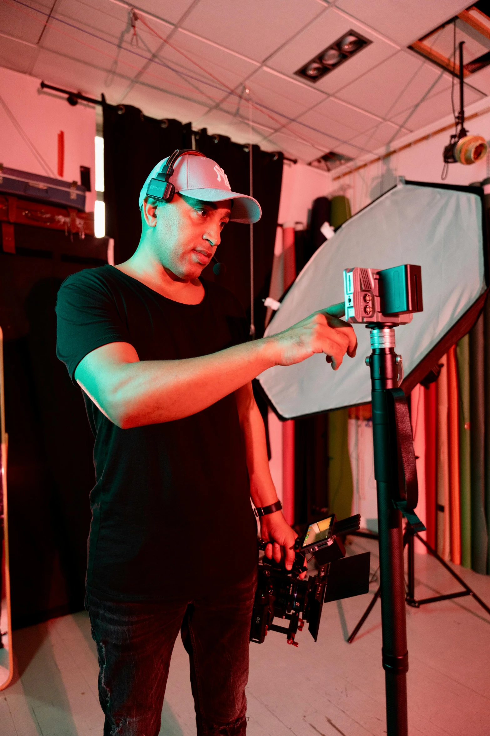 a man wearing a baseball cap pointing at the camera