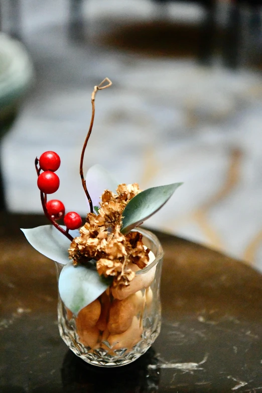 some red berries are arranged in a small glass vase