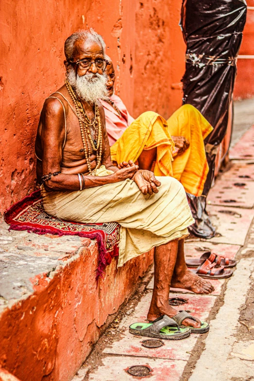 an elderly man sitting on a stone step with other people