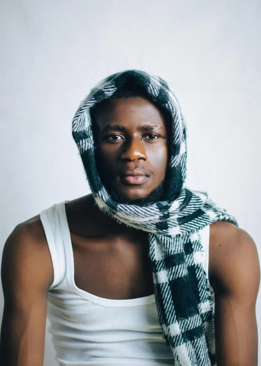 a man poses for a studio po wearing a scarf