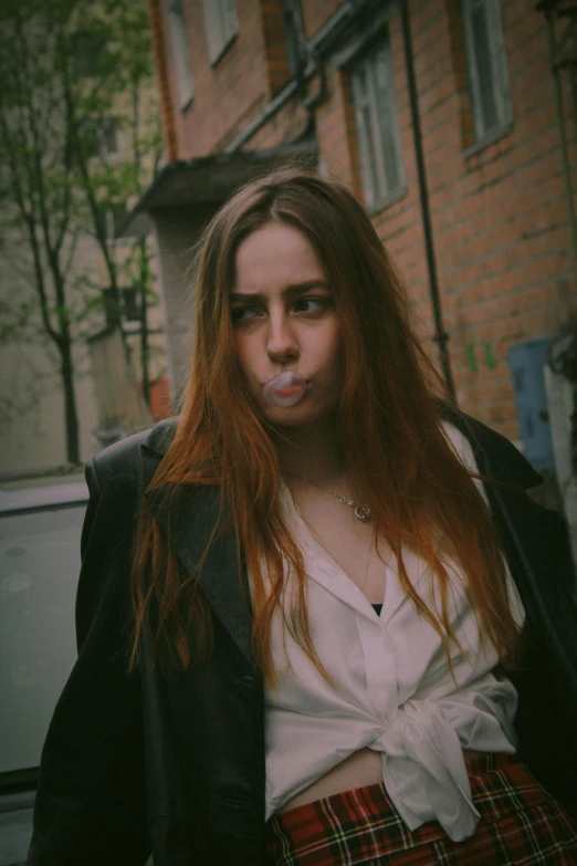 a woman with long red hair is posing outside