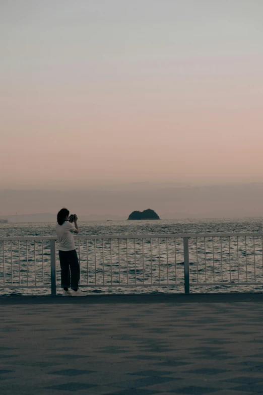 woman standing on a fence looking out over the ocean