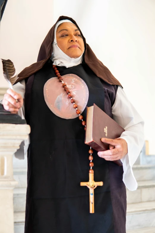 a woman dressed in nun costume holding a rosary and bible