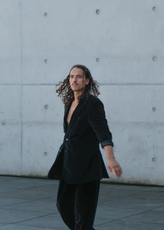 a man with long hair is walking with his arms in the air