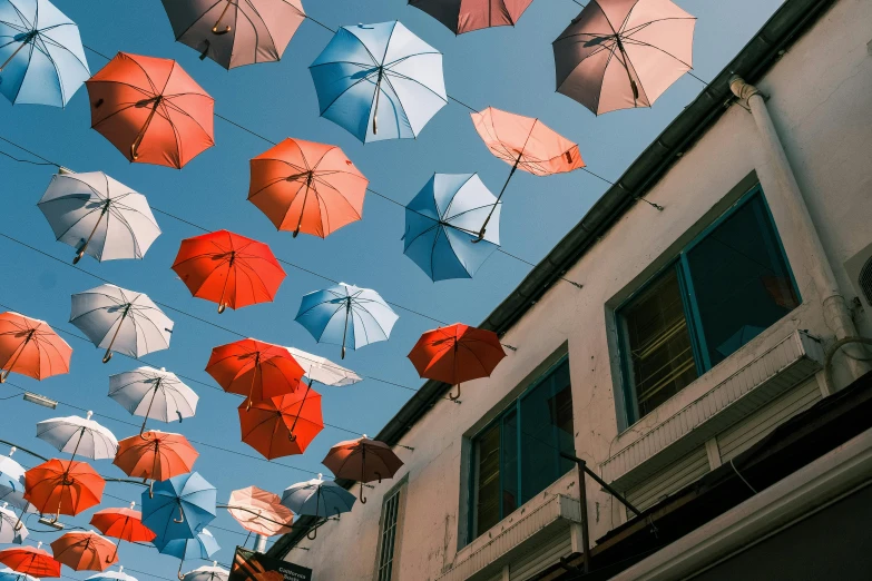 an assortment of different colored umbrellas over a building